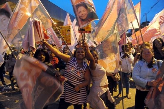 Mujeres bailando y agitando banderas con el rostro de Rousseff