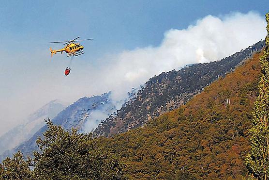 Un helicóptero lanza agua sobre una parte del cerro en Melipeuco 