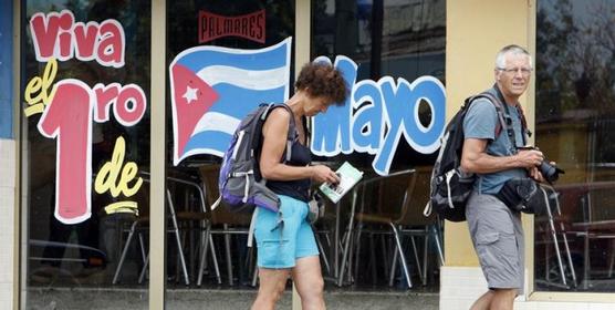 Dos turistas pasan frente a un cartel de convocatoria en La Habana