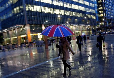 Trabajadores caminan bajo la lluvia en el distrito financiero de Canary Wharf, en Londres, ayer