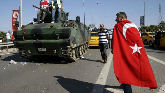 Un hombre envuelto con la bandera turca pasa delante de un vehículo militar en el aeropuerto de Estambul