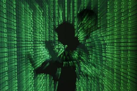 Ilustración fotográfica que muestra una proyección de códigos binarios sobre un hombre que sostiene una computadora portatil