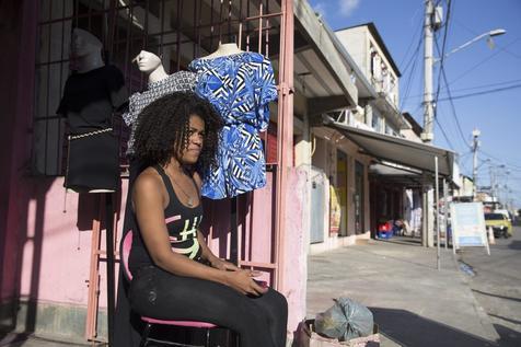 Una mujer intenta vender ropa en la puerta de su vivienda. El sub-empleo crece en Rio de Janeiro 