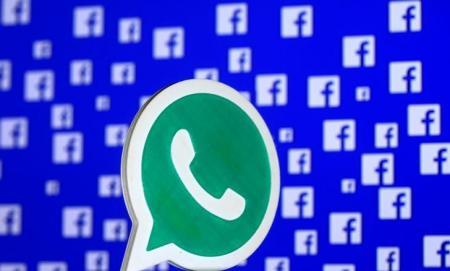 Logo de WhatsApp frente a una pantalla con múltiples logos de Facebook