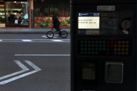 Un ciclista pasa junto a un parquímetro que advierte de los altos niveles de contaminación en el centro de Madrid