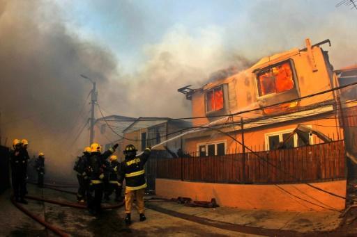 Bomberos trabajan para extinguir las llamas de una casa en Valparaíso, ayer