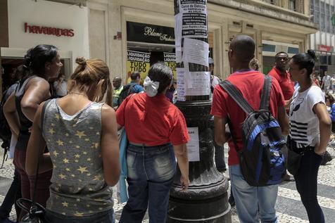 Jovenes paulistas leen cartelera callejera por trabajo