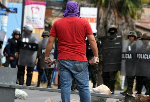 Manifestante opositor confronta a agentes policiales en el bloqueo de una vía en Tegucigalpa, ayer