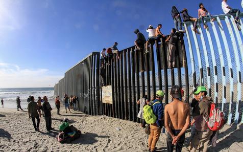 Migrantes centroamericanos trepan a la valla que divide México de Estados Unidos. Tensión en aumento. (foto: ANSA)