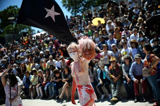 Una mujer sostiene una máscara del presidente de Chile, Sebastián Piñera, durante una performance ayer en Santiago
