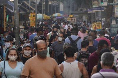 Transeúntes, la mayoría con mascarillas debido al coronavirus, recorren un mercado callejero en el centro de Río de Janeiro