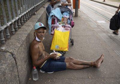 Hombre en Rio come el almuerzo donado por la Fundación Leao XIII durante la pandemia de COVID-19