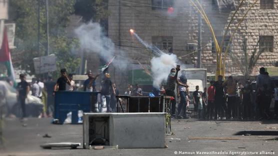 Manifestantes palestinos queman neumáticos y arrojan piedras durante una protesta contra los ataques de Israel, en Hebrón
