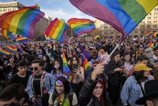 Personas ondean banderas de arcoíris al paso de los carros alegóricos durante una marcha por la diversidad sexual, en Santiago