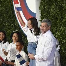 El presidente de Paraguay, Mario Abdo Benítez, alza a una niña que porta una bandera del país en Cumbre de Santo Domingo